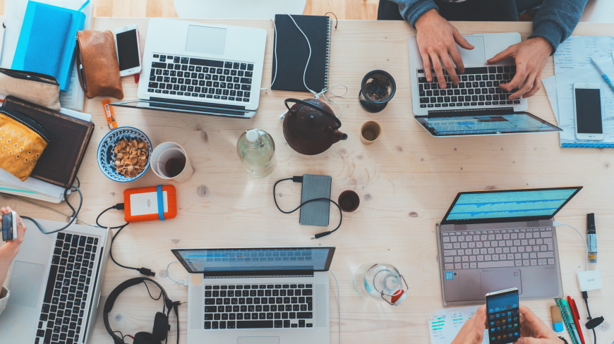 Laptops, mobiles and workers round a table