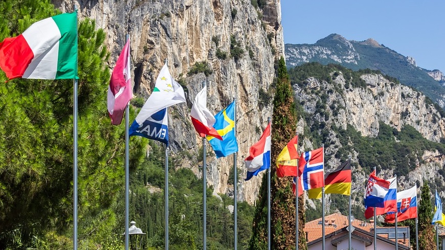 Several flags on flagpoles in mountainous setting