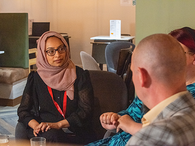 Picture of two women and one men sat around a table having a discussion