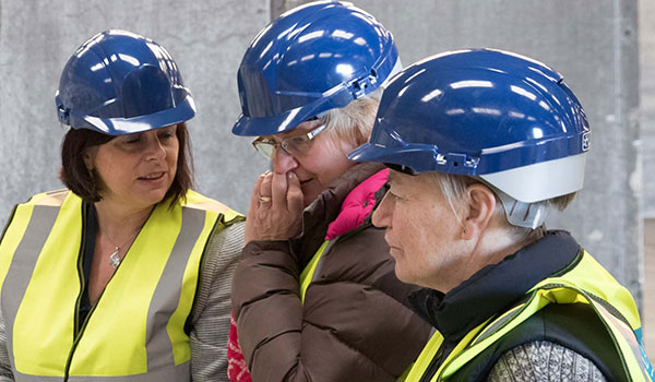 Three women with PPE on a business site