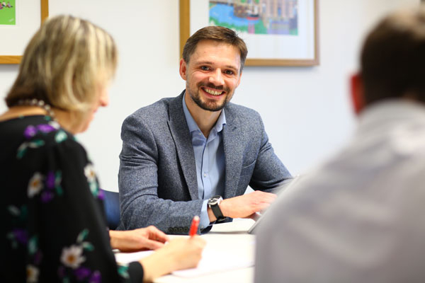 Three people sat round table in business meeting