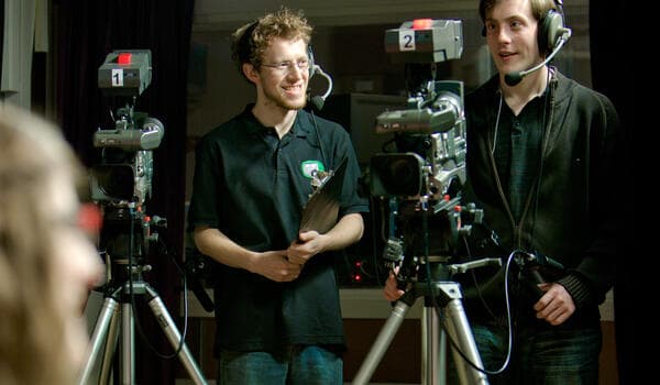 Two people with cameras recording a media interview