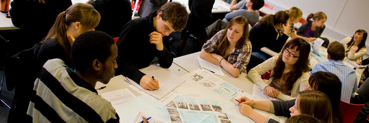 A group of people siting around a table working.