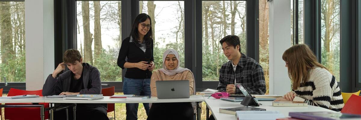 Group of students in a seminar room chatting with a lecturer