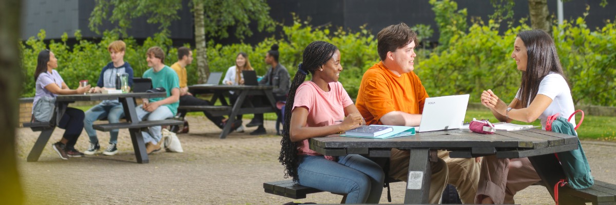 Groups of students sit at picnic tables near Pendle College