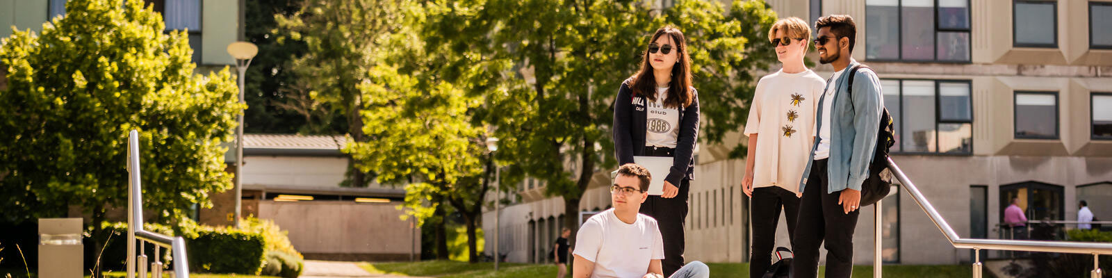 A group of students stood close to each other with a garden background