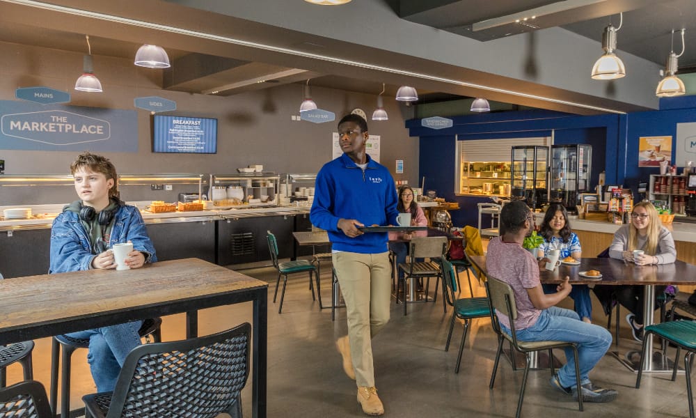 Students sit in a diner, eating and talking.