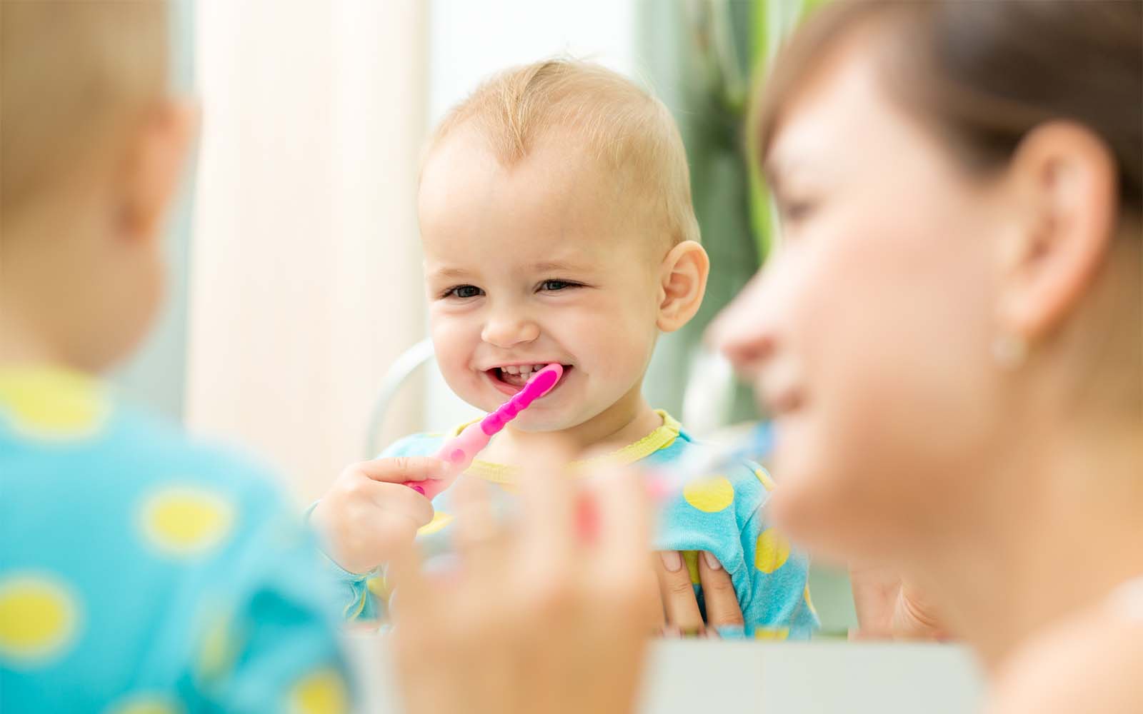 Baby having their teeth brushed by parent