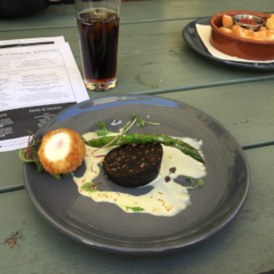 Eating scotch egg and black pudding at an outdoor pub table