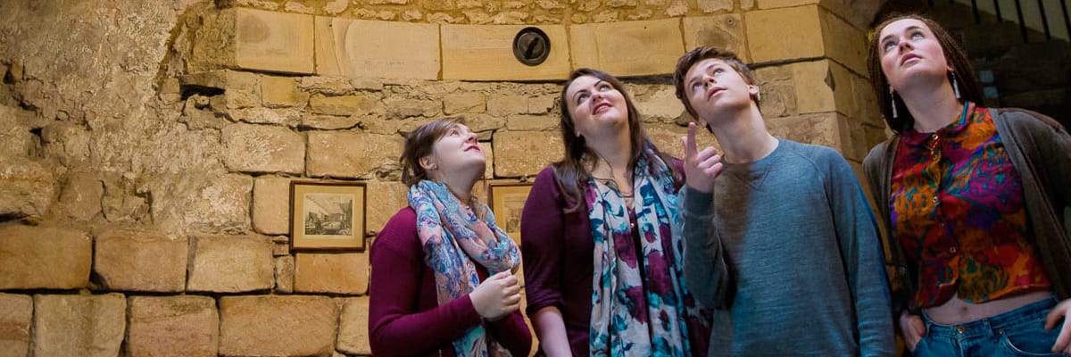 Four students look at the ceiling of a room in Lancaster Castle.