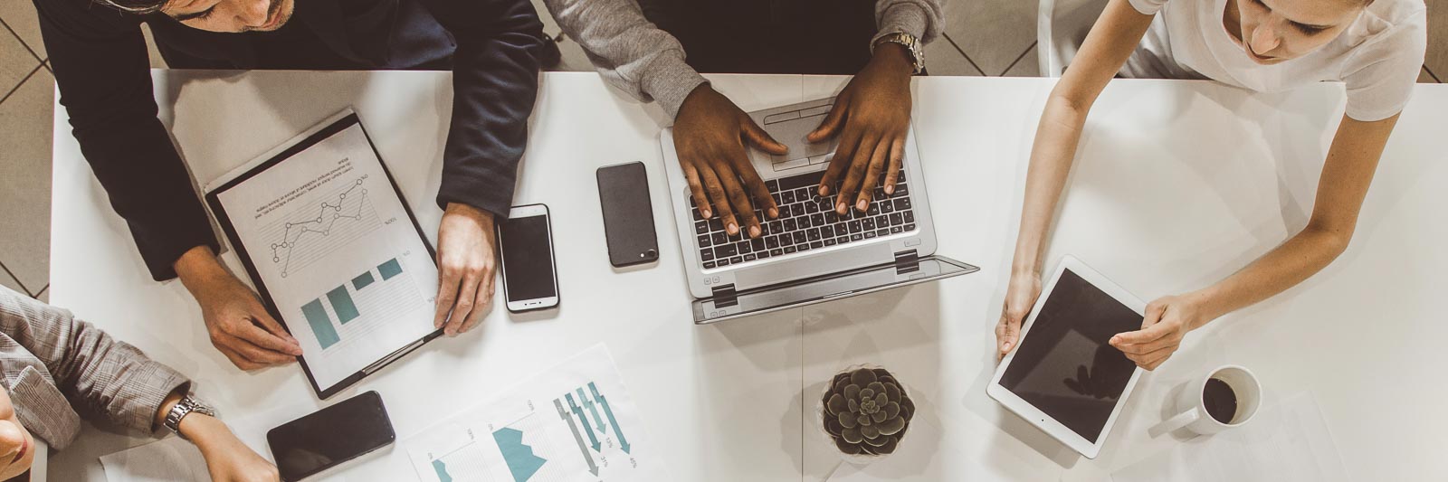 People sitting around a desk working from laptops. The image is shot from directly overhead.