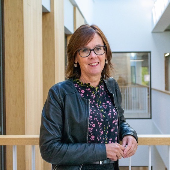 Jo Rycroft-Malone with brown wavy hair, glasses smiling.