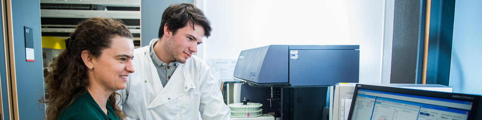 A technician tutors an intern working in a laboratory