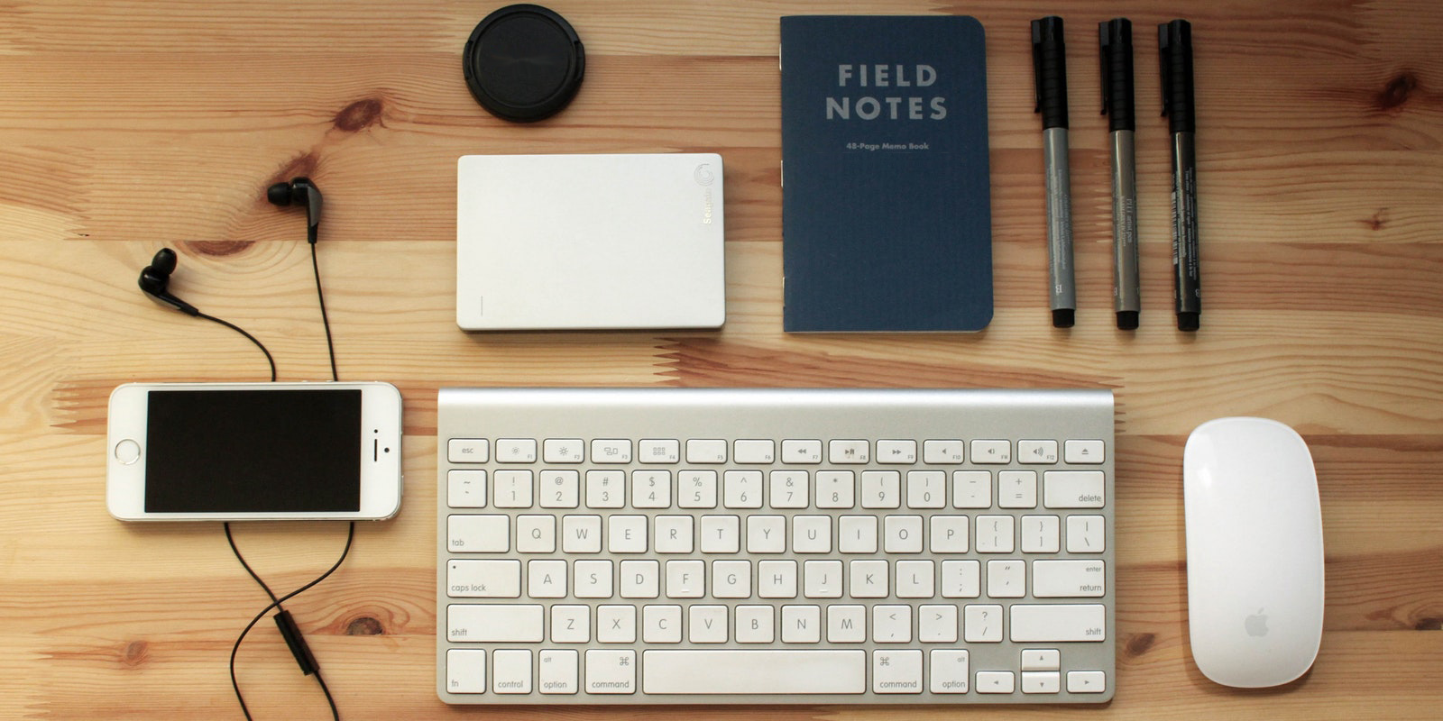 Keyboard, mouse, notebook, phone and pens on desk