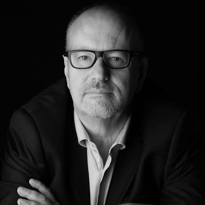Professional portrait of Stephen Wilkinson, a man with glasses wearing a dark jacket, arms crossed