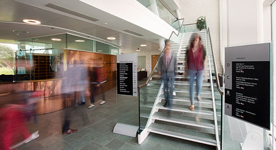 Two people walking downstairs in a spacious foyer.