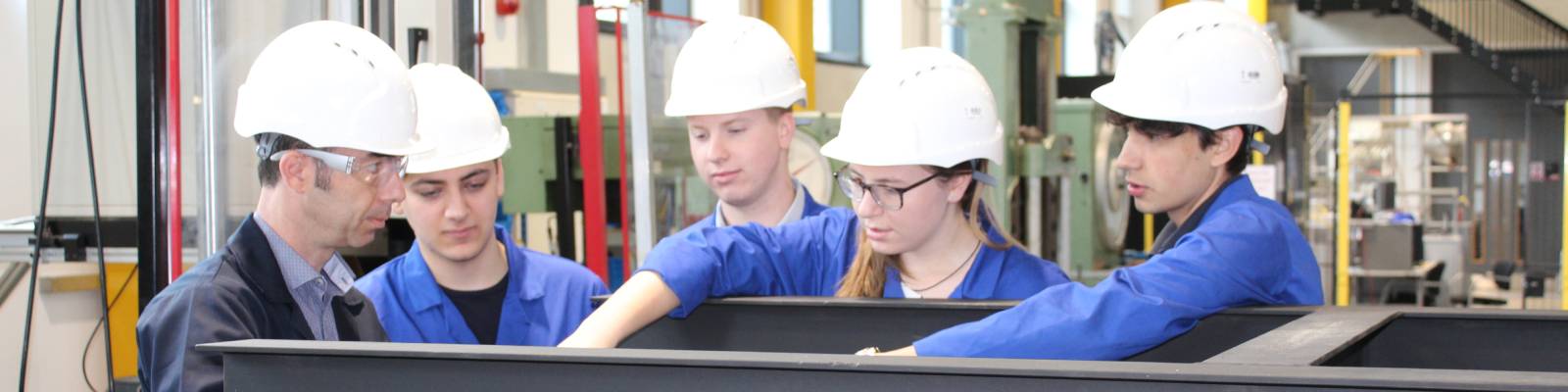 Four students in a workshop, discussing equipment with a technician