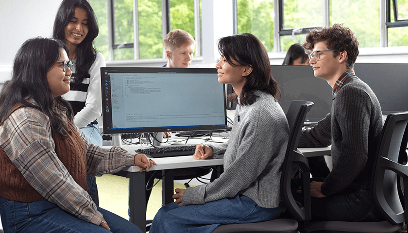 A group of students sat by a computer