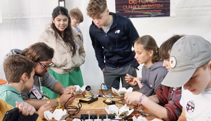 A group of teenagers participating ina physics activity at WOMAD
