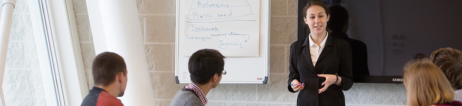 A woman in a suit presenting to a boardroom