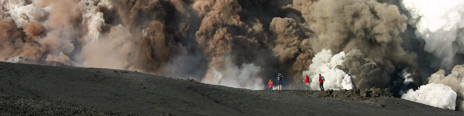 Students on a field trip to Etna stand in front of a billowing eruption
