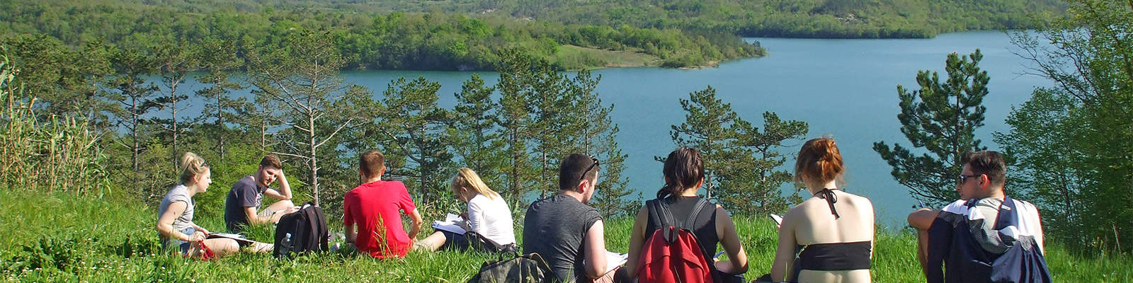 A group of students sit on the grass taking readings