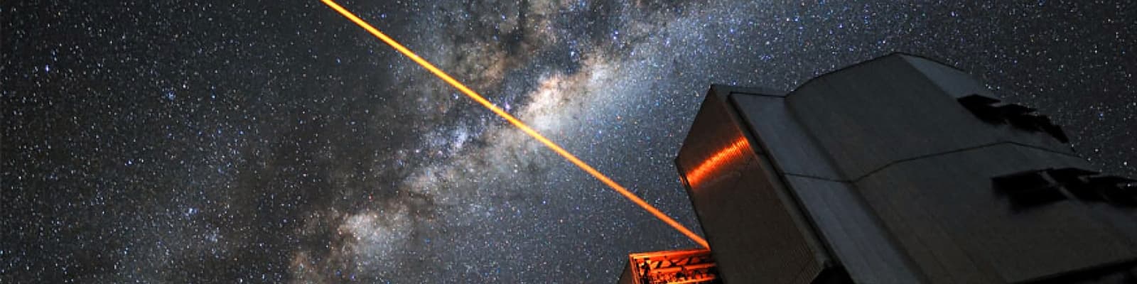 A beam of light leaves a telescope dome at night
