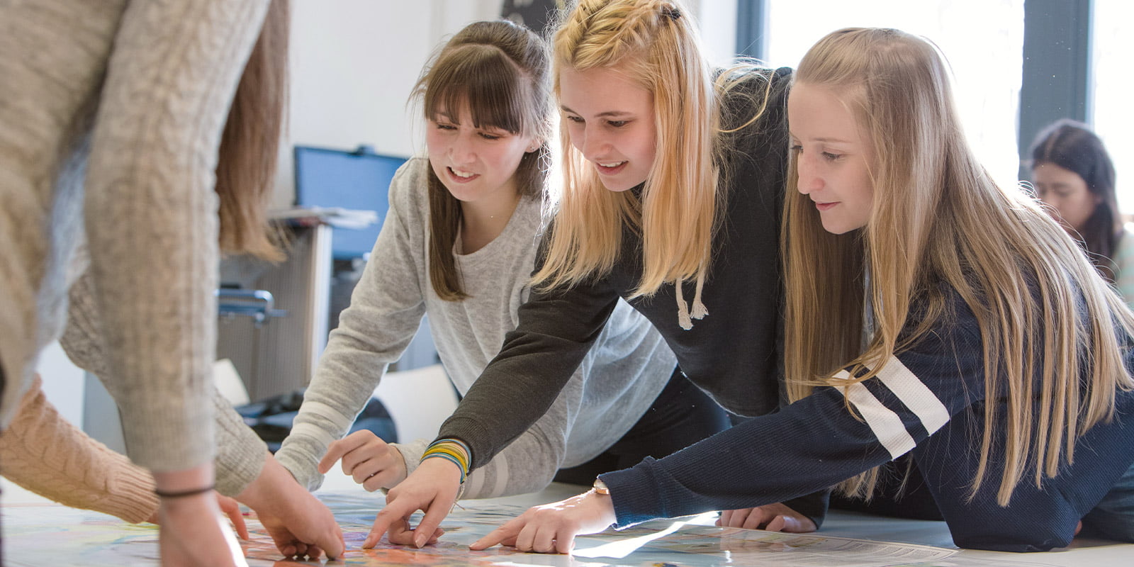 Geography students point to a map