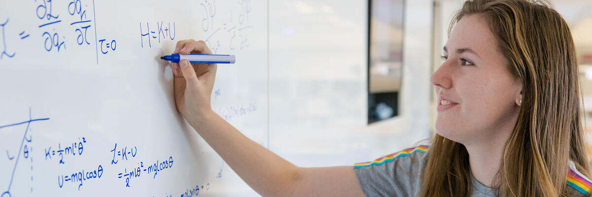 A student writing equations on a board