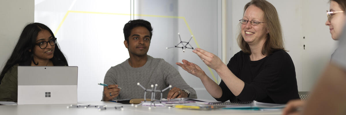 An academic holding a chemical model for students in a seminar group