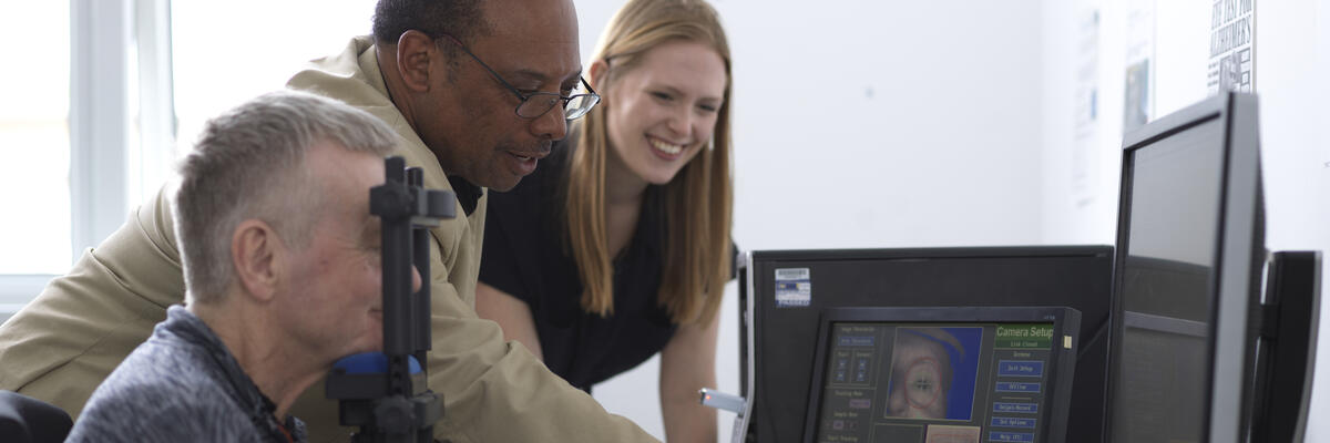 An academic and a student performing an eye-tracking test on an older man