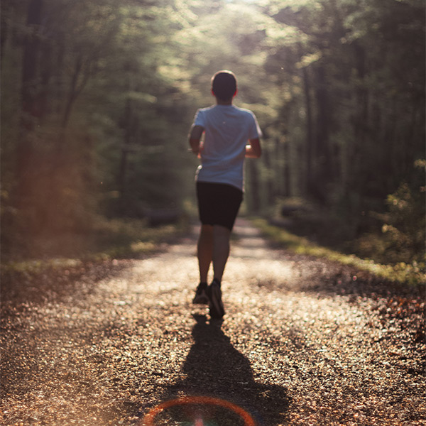 A person jogging on a path through the woods