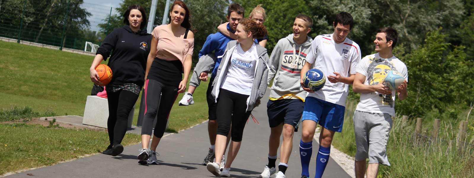 Furness students walking towards camera with some balls by the sports pitches