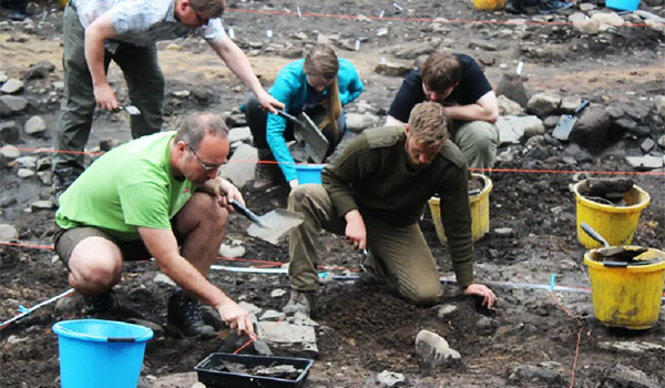 Students looking at potential artefacts in the ground as part of archaeology studies