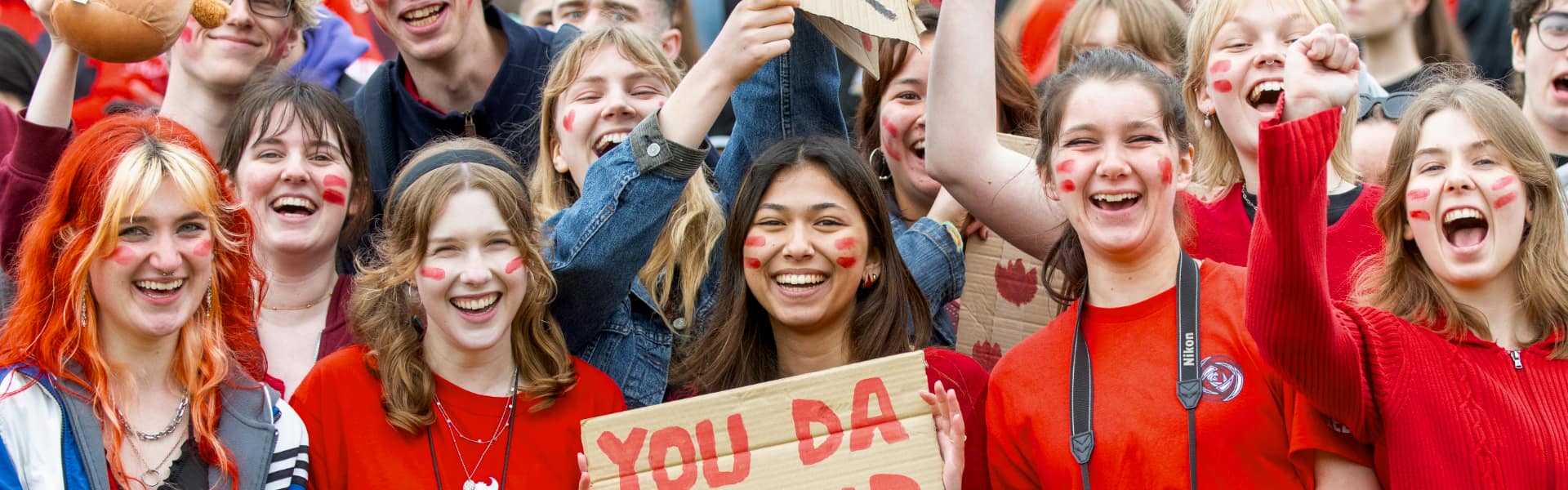 A crowd of students in red cheer on Lancaster at a Roses tournament