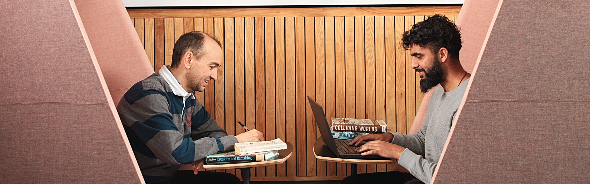 Two students sit at a desk in the postgraduate study centre and working.