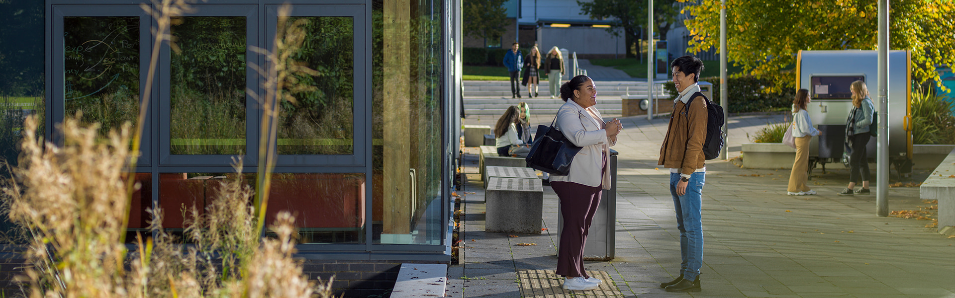 Students chatting next to LICA building in autumn 