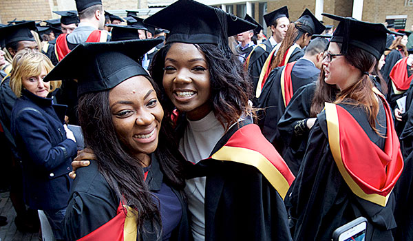 Graduates in robes and mortarboards celebrating outside Lancaster's great hall