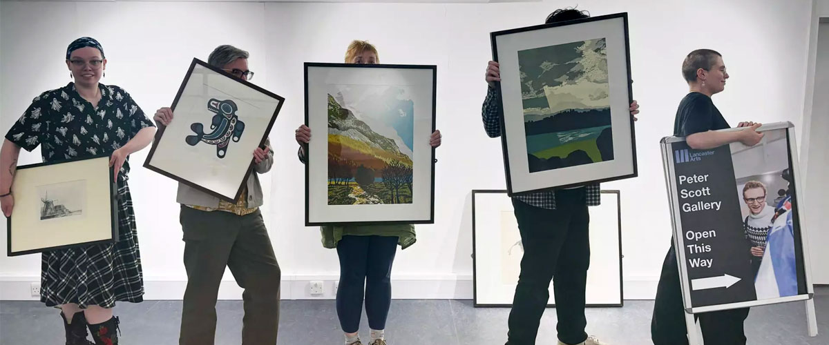 Photograph of five artists holding framed artwork