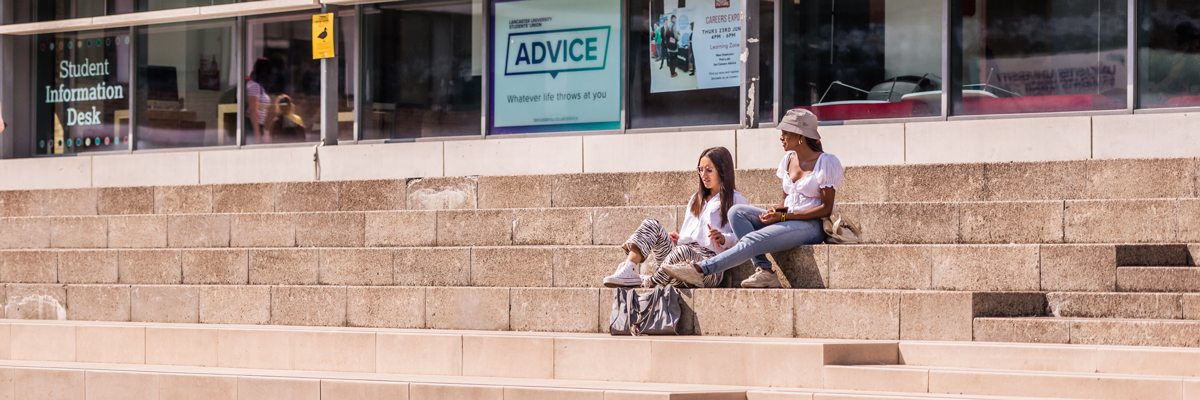 Two students sitting and talking on the steps in Alexandra Square