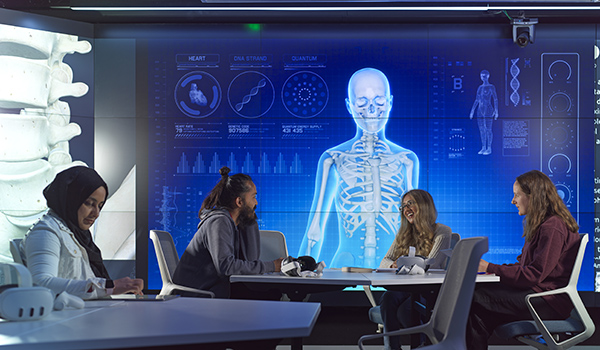 People working at a table with health data showing on large screens.