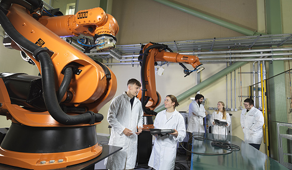 A group of researching working on a robotic arm.