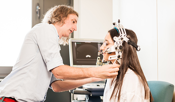 A linguistics researcher attaching equipment to a study participant.