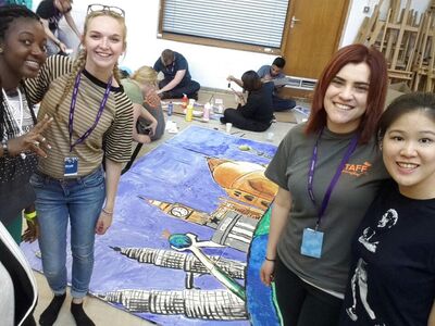 A diverse group of students posing next to an art project.