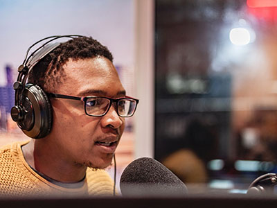 A man with headphones on speaking into a microphone.