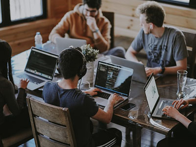 A group of people with laptops sitting around a glass table.