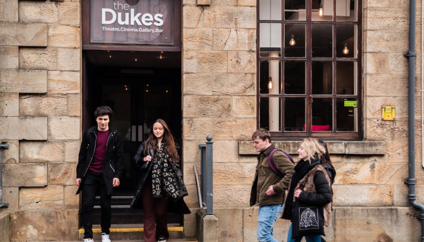 Students walk out of the front door of the Dukes Theatre.
