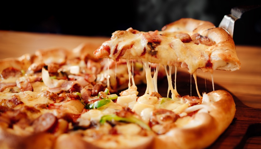 A slice of pizza is extracted from a larger pizza.