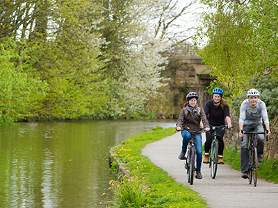 Three people cycling beside the canal.