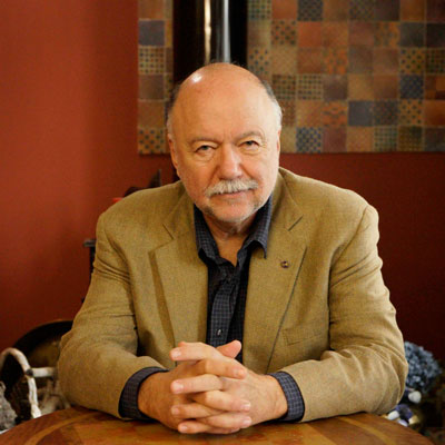 Andrew Kourkov sitting at a table in a smart jacket with hands together